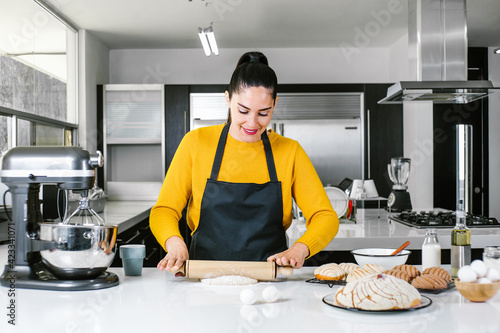 Latin Woman standing in kitchen and kneading dough to bake Conchas traditional Mexican bread