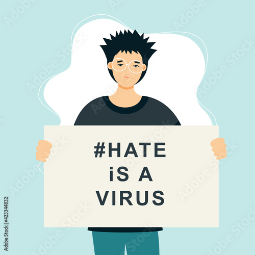 Stop Asian Hate‬‬. Hashtag to support asian community during the covid-19 pandemic. Stop racism. Man wearing protective face mask and holding banner against bullying, hate and violence.

