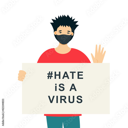 Stop Asian Hate‬‬. Hashtag to support asian community during the covid-19 pandemic. Stop racism. Man wearing protective face mask and holding banner against bullying, hate and violence.

