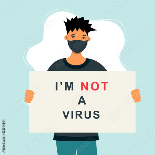Stop Asian Hate‬‬. Hashtag to support asian community during the covid-19 pandemic. Stop racism. Man wearing protective face mask and holding banner against bullying, hate and violence.

