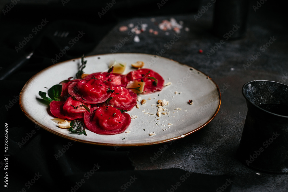 beet ravioli in a light plate on a dark background