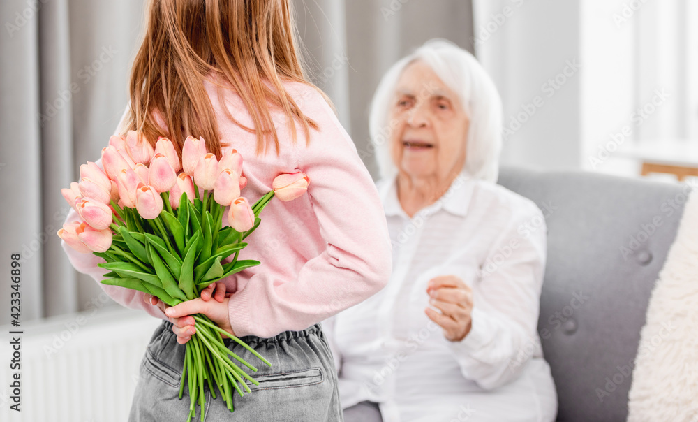 Grandaughter gives flowers to grandmother Grandaughter gives flowers to grandmother
