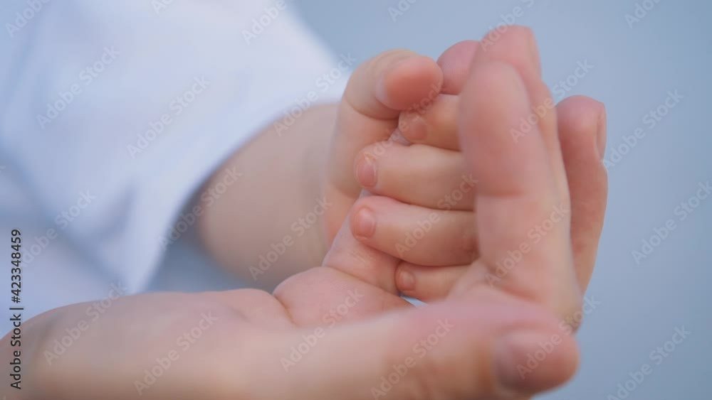 Happy family concept.Baby and mother's hand close up. Mother's hand holds a newborn baby with her fingers. Parts of the body of a newborn baby. Happy family concept.Baby and mother's hand close up. Mother's hand holds a newborn baby with her fingers. Parts of the body of a newborn baby.