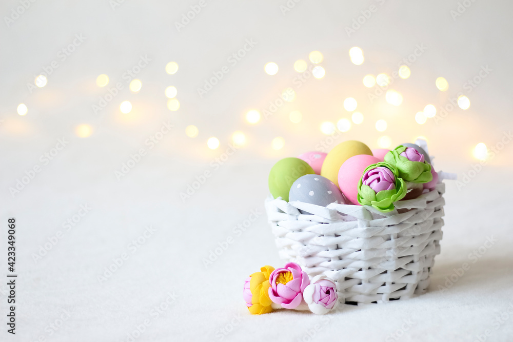 A white wicker Easter basket with colorful eggs and bokeh lights in the background.