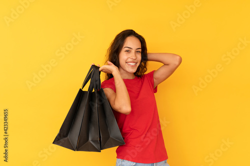 Young woman on shopping with black bags over color background