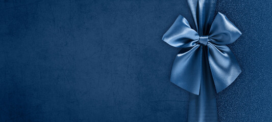 gift card with bright and shiny ribbon bow isolated on blue grunge background, top view and copy space template, layout useful for best wishes and shopping concept