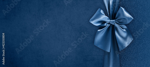 gift card with bright and shiny ribbon bow isolated on blue grunge background, top view and copy space template, layout useful for best wishes and shopping concept