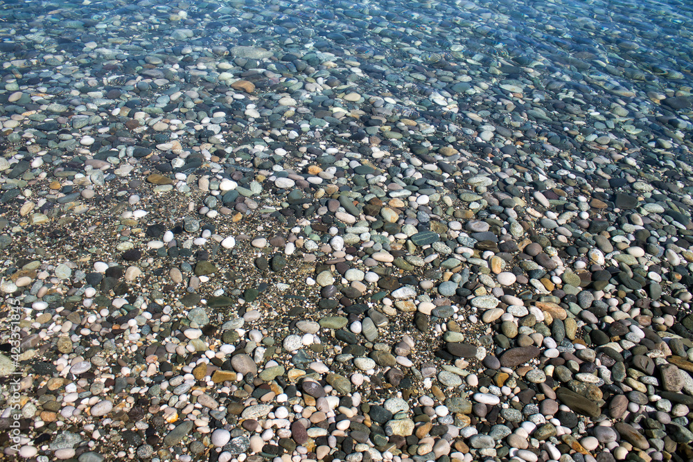 Sea stones in sea water. Pebbles under water. The view from the top. Nautical background. Clean sea water. Transparent sea Sea stones in sea water. Pebbles under water. The view from the top. Nautical background. Clean sea water. Transparent sea