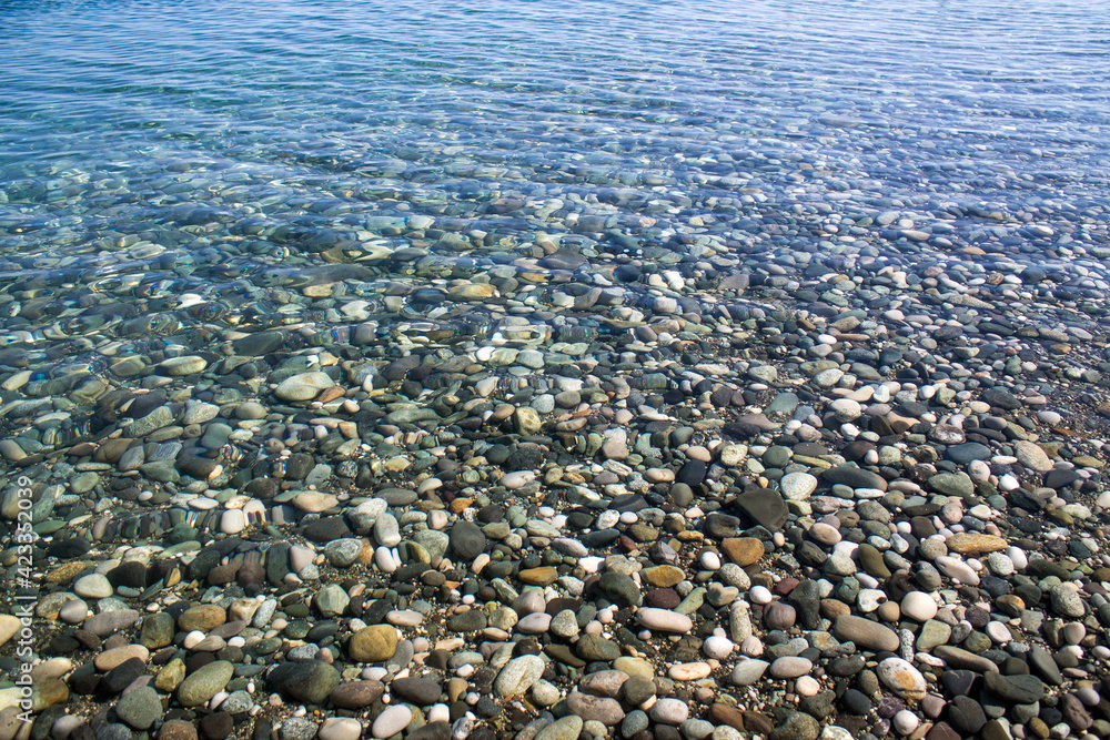 Sea stones in sea water. Pebbles under water. The view from the top. Nautical background. Clean sea water. Transparent sea Sea stones in sea water. Pebbles under water. The view from the top. Nautical background. Clean sea water. Transparent sea