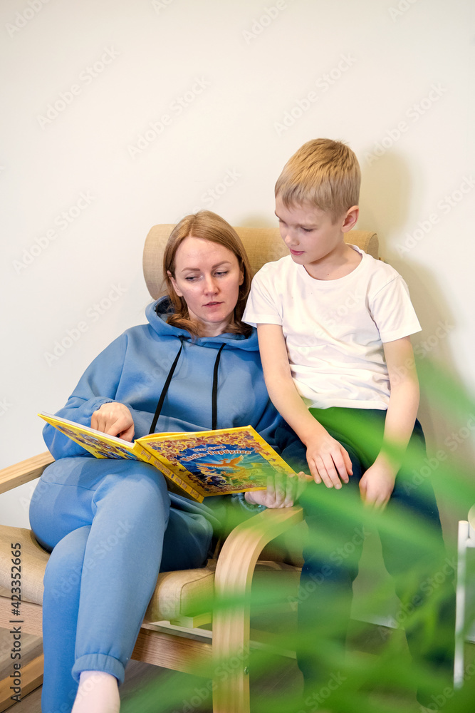 Happy Caucasian mother reads a book with her young son. Mom and child learn together, a happy single parent concept.