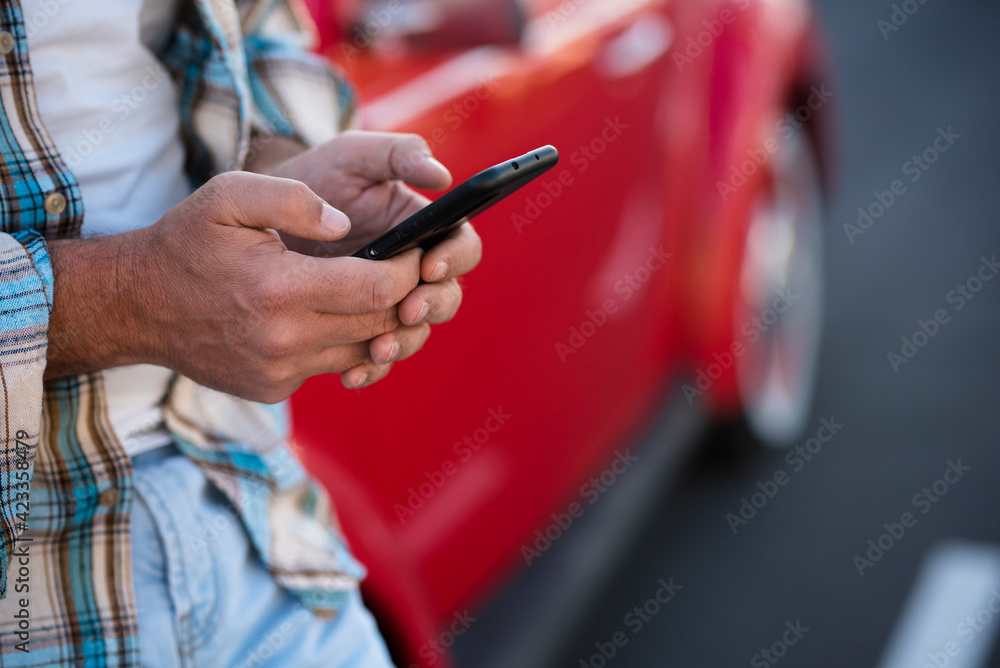 Close up of man using phone outdoor - unrecognizable people with cellular smartphone chatting or texting with car in background - modern lifestyle with everywhere roaming connection Close up of man using phone outdoor - unrecognizable people with cellular smartphone chatting or texting with car in background - modern lifestyle with everywhere roaming connection