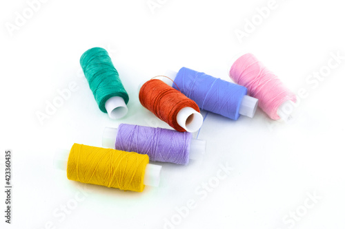 threads on bobbins multi-colored yellow, lilac and blue on a white isolated background