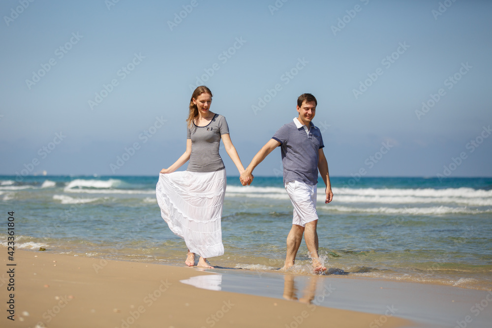Young man woman on sea vacation. Couple funny run on a tropical beach at sunny day, enjoying summer holidays. Summer lifestyle portrait of pretty young lovers. Vacation travel in tropic country