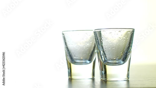 strong alcohol pouring into shot glasses on white background