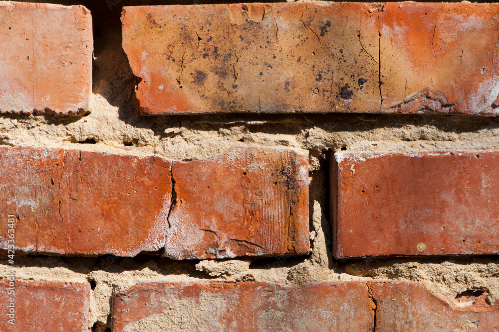 old brick wall. Decorative wall made of destroyed dark red bricks. Background for design on a construction or architectural theme. cracked cement joint. red brick close up. may use to interior design old brick wall. Decorative wall made of destroyed dark red bricks. Background for design on a construction or architectural theme. cracked cement joint. red brick close up. may use to interior design