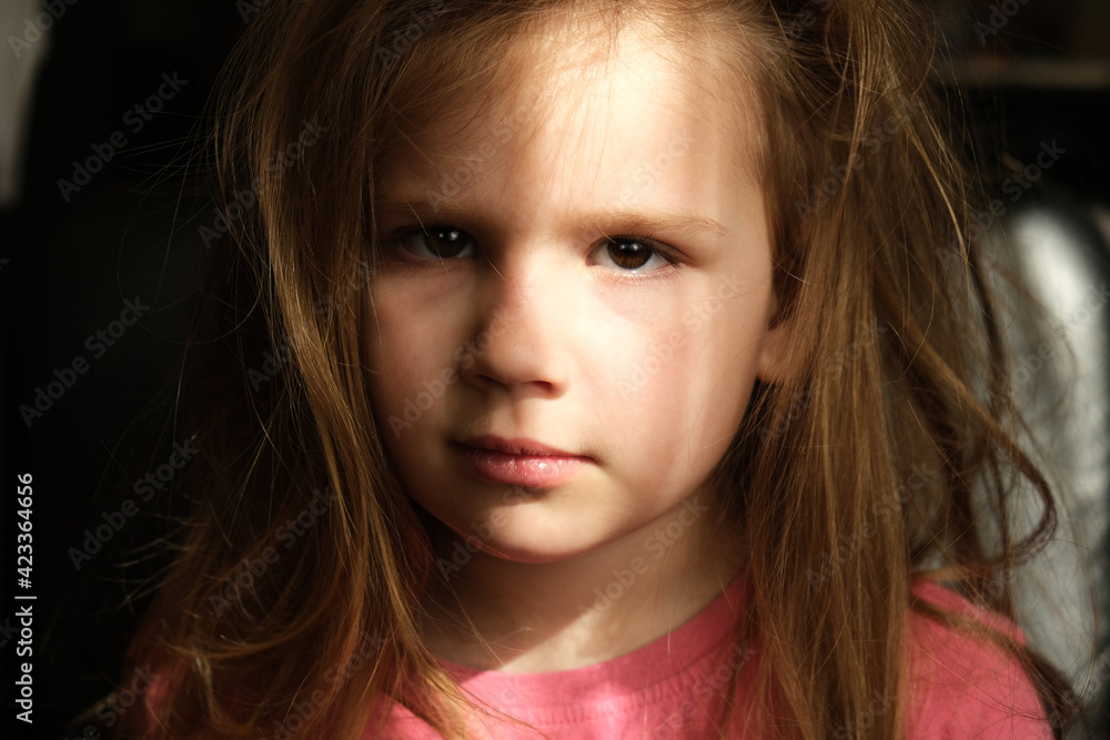 Dramatic portrait of beautiful sad little child girl with shadow on face. lonely in dark. Childhood and problems of parents and children concept. unknown and extraordinary child's soul and inner world Dramatic portrait of beautiful sad little child girl with shadow on face. lonely in dark. Childhood and problems of parents and children concept. unknown and extraordinary child's soul and inner world