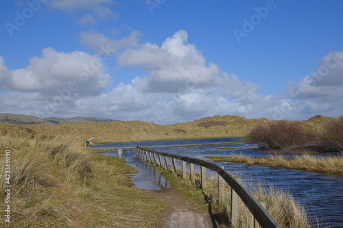 a gangway going over some sand dunes leading to a flooded lake at the bottom
