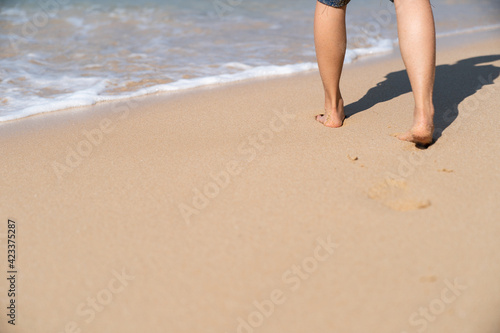 Footprints in the sand on the beach. Woman walking to the sea.