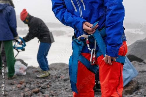 Mountain climber (girl) puts on harness.