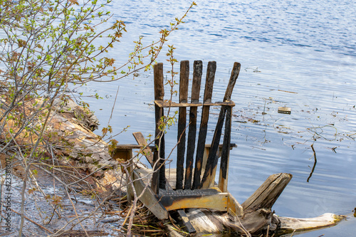 An old wooden camp chair washed up on a riverbank after spring flooding brought havoc to the area