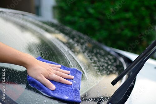 Man cleaning car with microfiber cloth at car wash