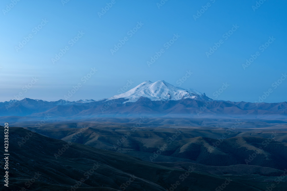 Late blue hour view of Mount Elbrus from Bermamyt plateau. Karachay-Cherkessia, Caucasus, Russia.