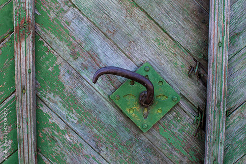 Vintage antique metal door knob or handle on wooden door with peeling green paint