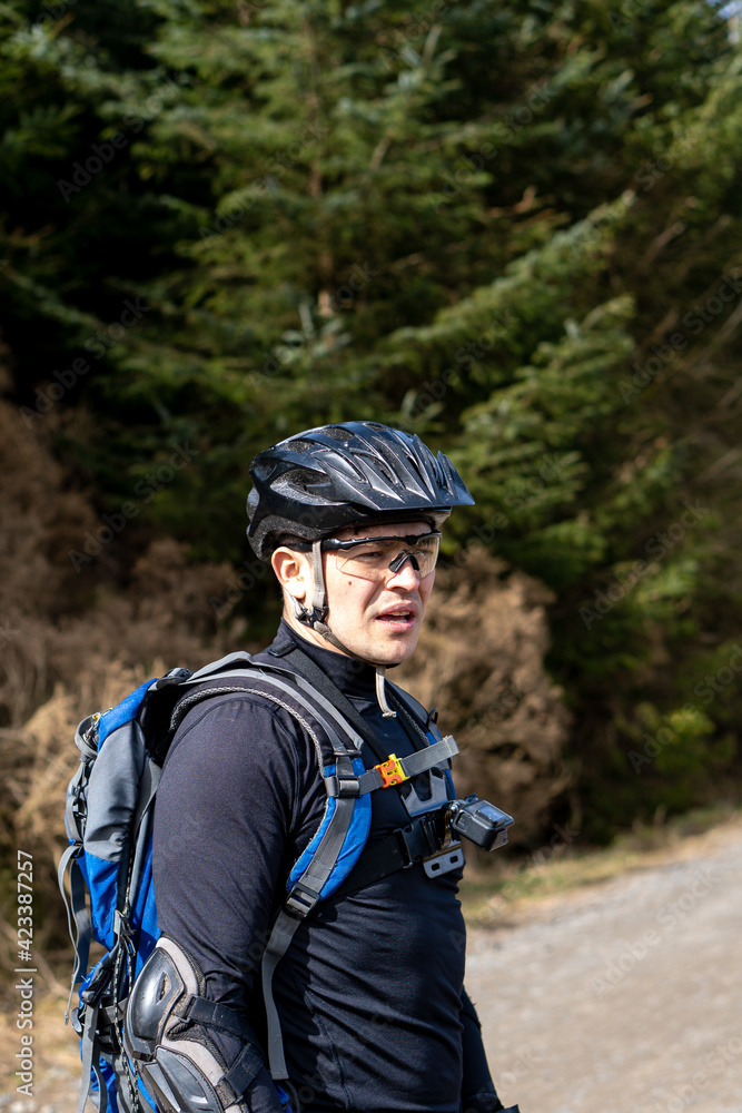 Mountain biker with his helmet and backpack in forest Mountain biker with his helmet and backpack in forest