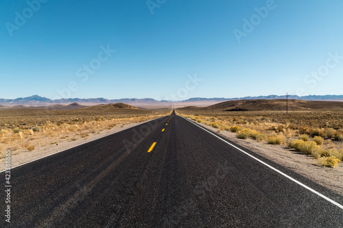 Road disappearing into the distance in desert landscape.