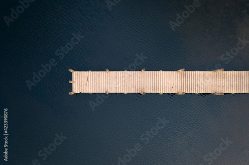 Fotografie Birds eye view of wooden jetty leading out over lake taken with drone