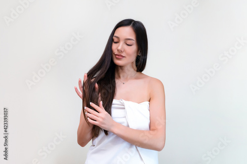 Hair care. Beautiful young woman in a towel touches her hair