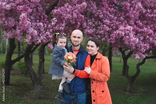 young happy family in the park in spring on the background of a flowering tree