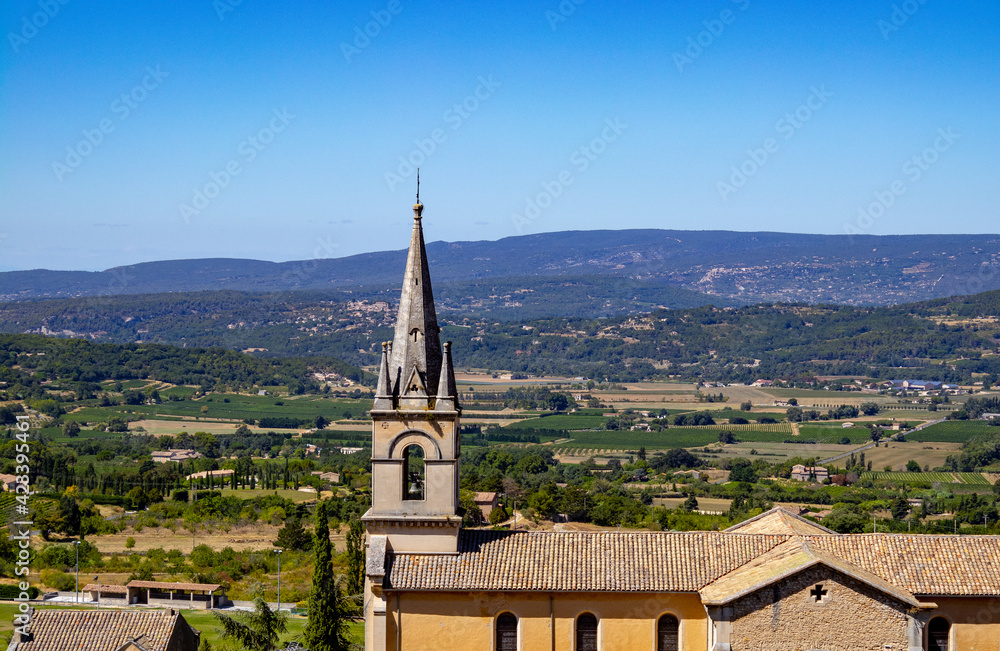 Bell tower from close in a cute little village in provence with a countryside landscape in France as background by a wonderful cloudless sunny day 