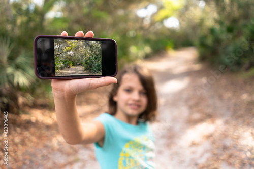 Young girl showing a photograph on a smartphone device while hiking outdoors in nature