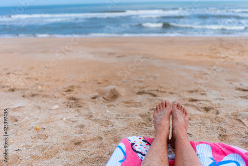 Sandy feet on a beach with ocean in background