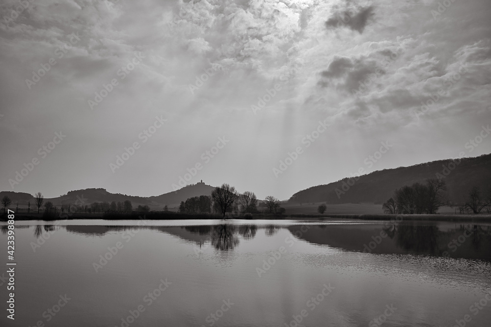 Fototapeta premium See am morgen mit Spiegelung von einem Berg und einer Burg