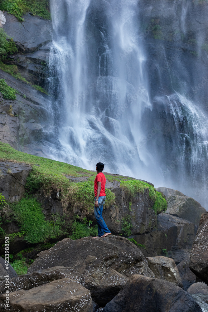 A boy standing next to a waterfall