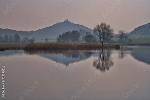 See am morgen mit Spiegelung von einem Berg und einer Burg