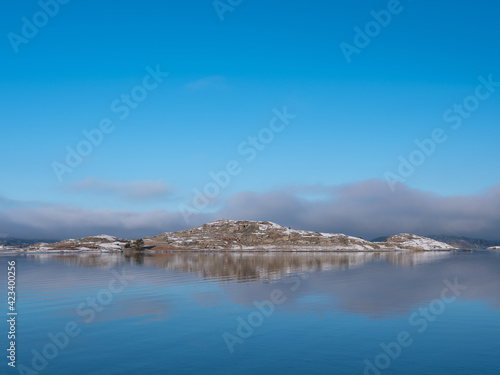 Bare islands with snow and purple cloud reflections in the sea.. Desolate feeling. Shot in Sweden, Scandinavia