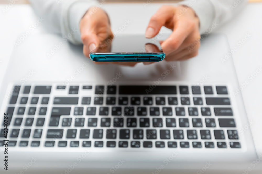 Woman's hands use mobile phone and laptop to shop online. Authentication in Internet banking on a smartphone and computer. Woman's hands use mobile phone and laptop to shop online. Authentication in Internet banking on a smartphone and computer.