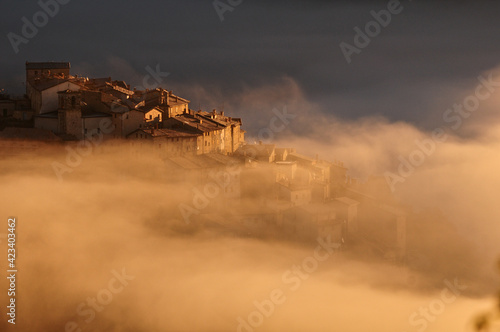 Fotografie Early morning fog engulfs the hilltop village of Castelluccio di Norcia, Umbria,