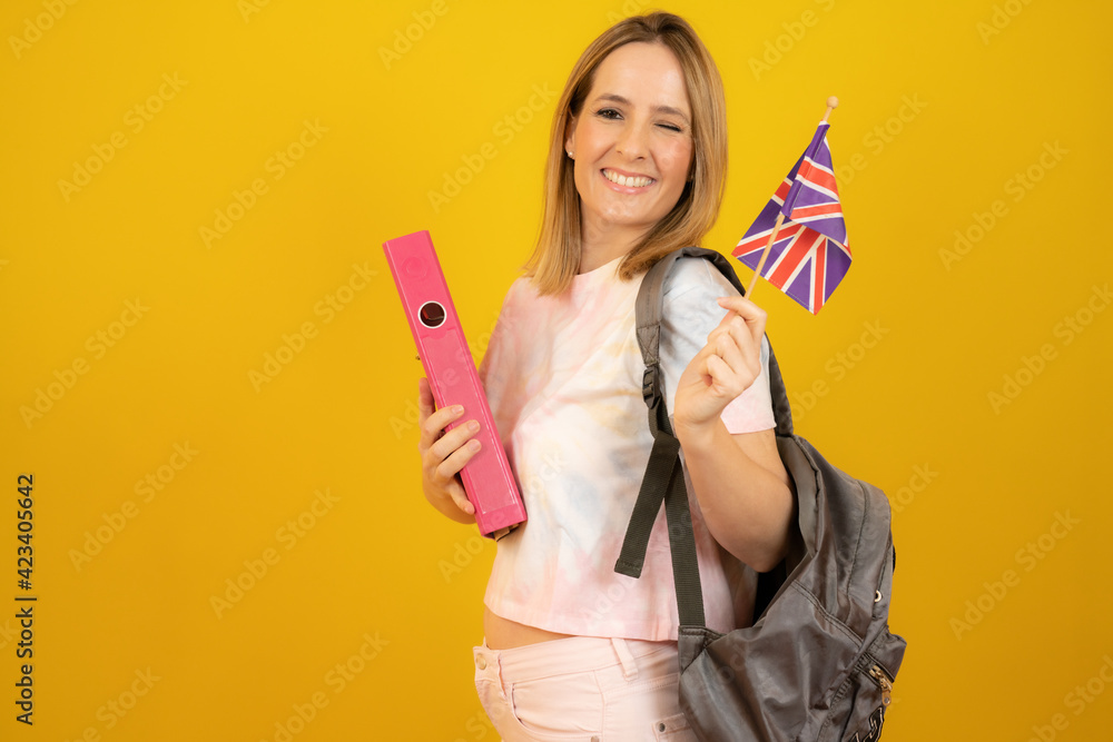 Beautiful blonde woman with the flag of Great Britain over yellow background. Beautiful blonde woman with the flag of Great Britain over yellow background.