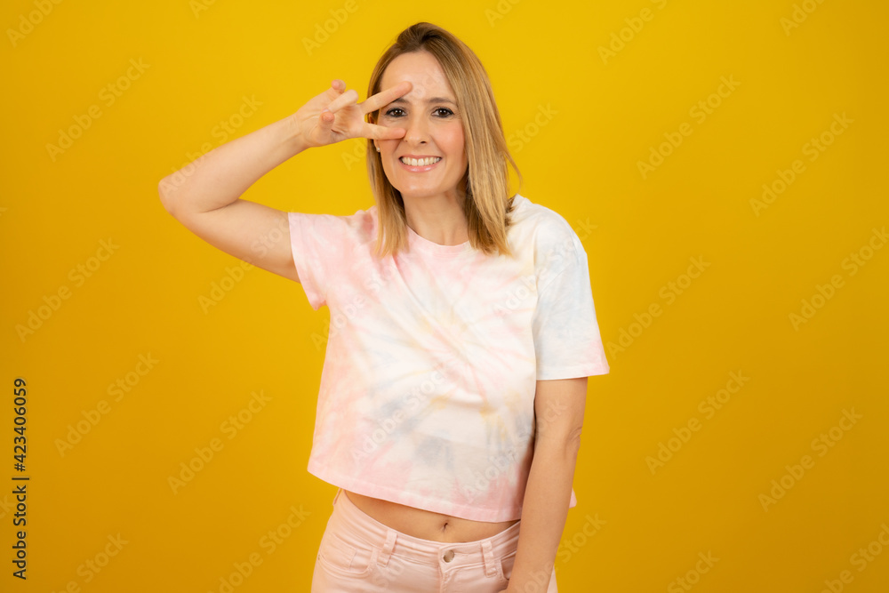 Young woman isolated showing victory sign and smiling broadly. Young woman isolated showing victory sign and smiling broadly.