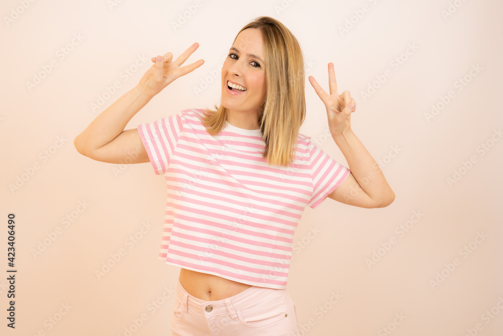 Young woman isolated showing victory sign and smiling broadly. Young woman isolated showing victory sign and smiling broadly.