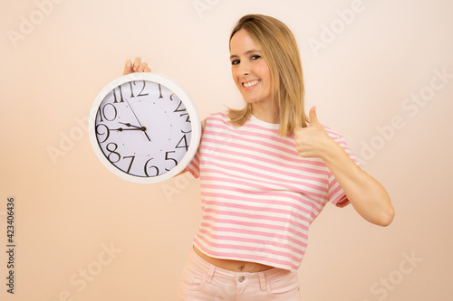 Young happy woman holding a big clock over white background