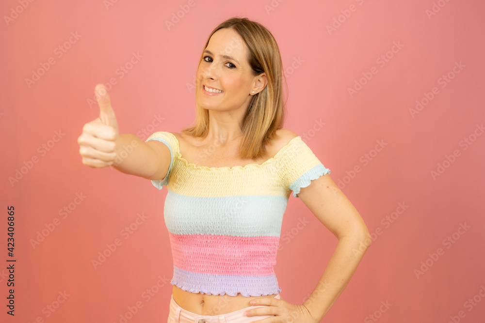 Smiling pretty young woman showing thumb up isolated over pink background Smiling pretty young woman showing thumb up isolated over pink background