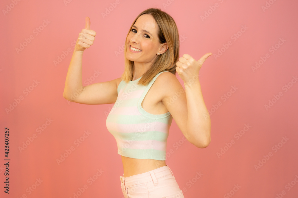 Smiling pretty young woman showing thumbs up isolated over pink background Smiling pretty young woman showing thumbs up isolated over pink background