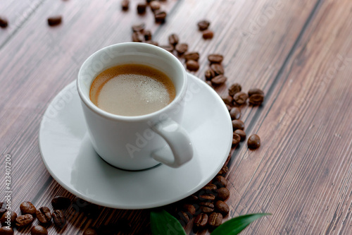 Cup of hot coffee on wooden table, surrounded by coffee beans