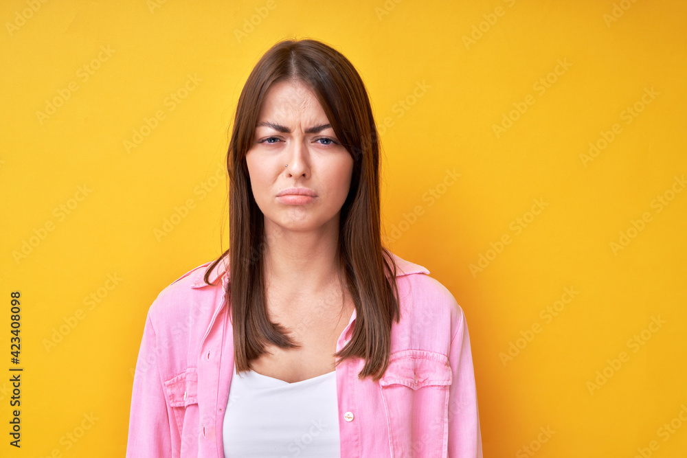 Fototapeta premium Young brunette woman with offended upset face isolated in yellow studio
