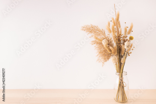 Bouquet of beige dried flowers in a glass vase on beige background. photo